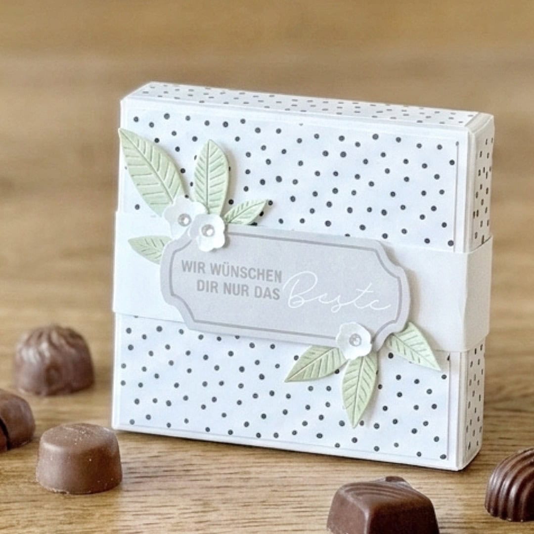 Mini-Geschenkbox aus einem Blatt Papier mit Banderole und Pralinen